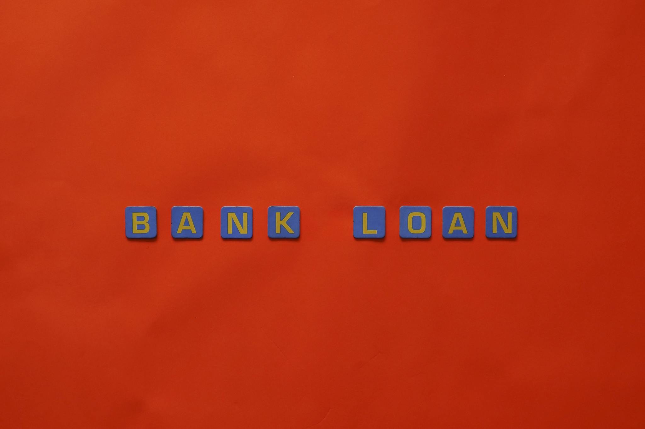 Letters forming 'Bank Loan' on a vibrant red surface, ideal for finance themes.